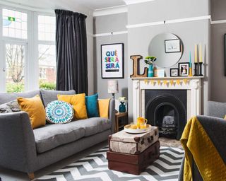 A blue and yellow living room with two stacked vintage trunks