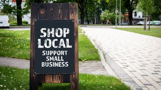 Shop Local. Support small business. Wooden billboard on the street, sunny day.