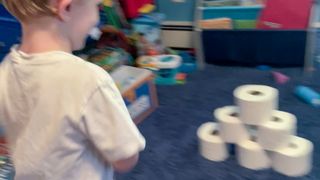 child bowling with toilet paper