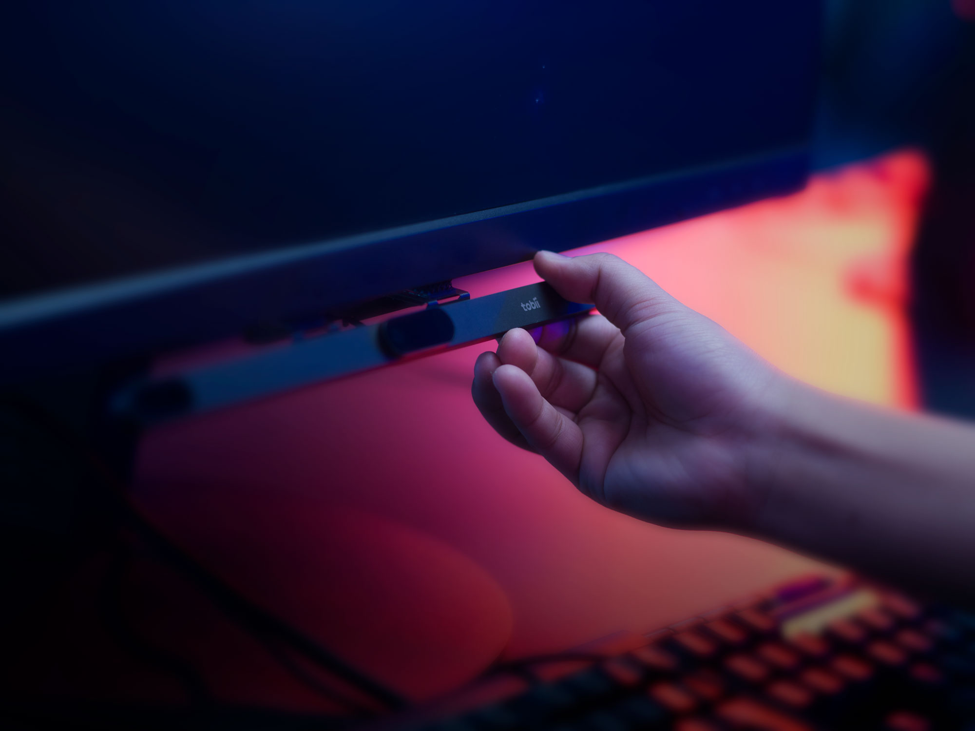 En person som plockar bort en Tobii Eye Tracker 5 från sin datorskärm.