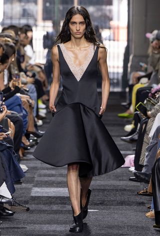 a model on the JW Anderson spring 2025 runway wearing a black structural drop waist dress