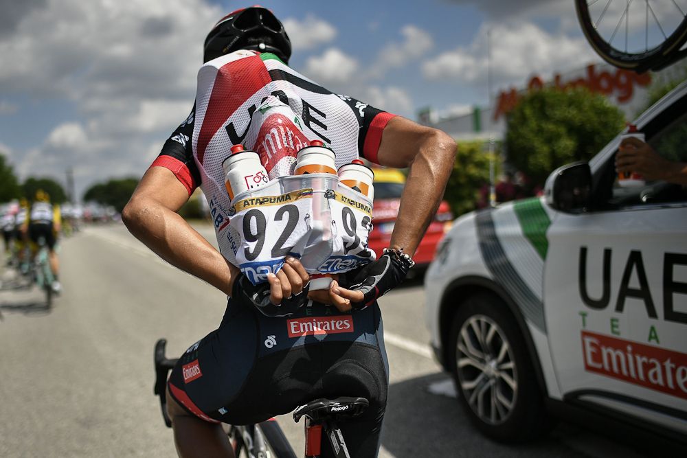 A UAE Team Emirates rider loads up with water bottles