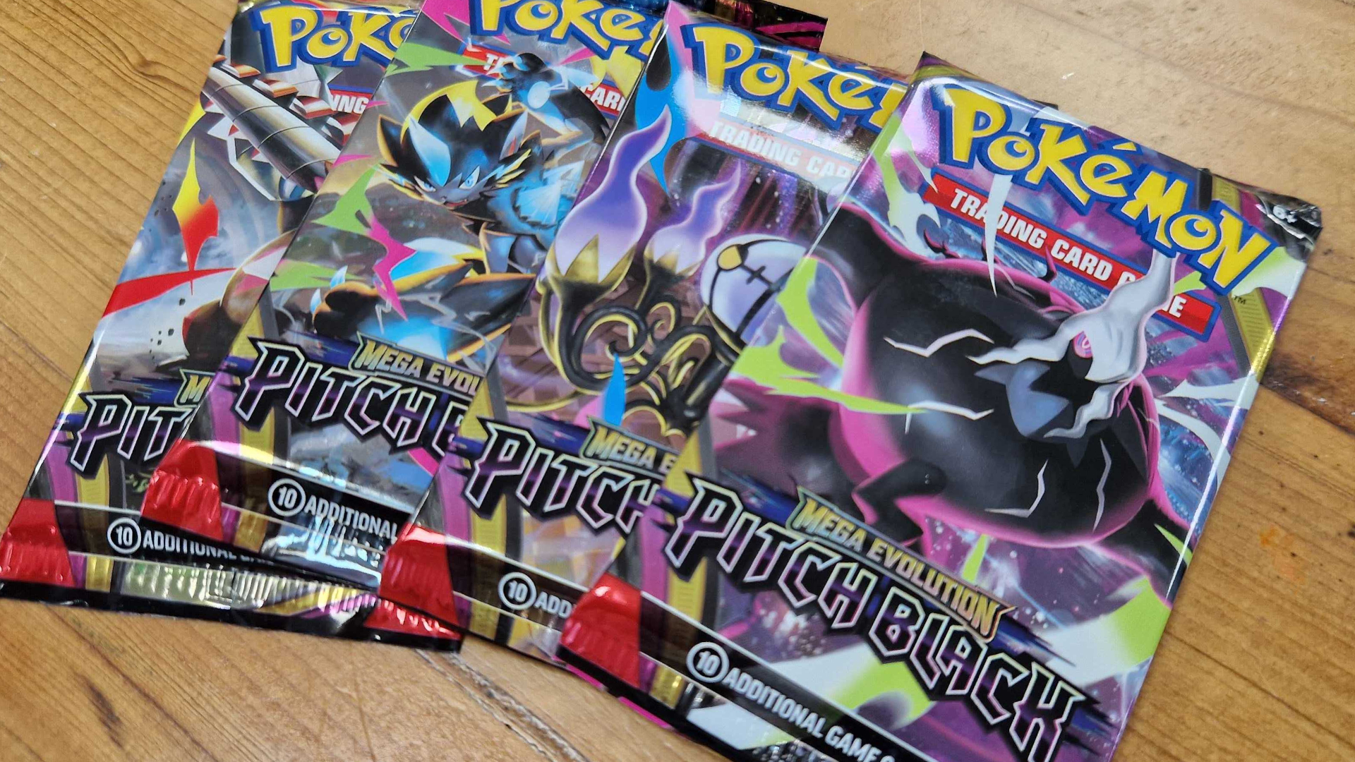 Pokemon Pitch Black boosters laid out on a wooden table