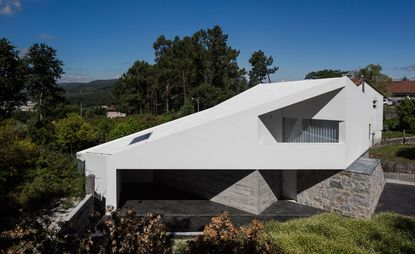Above the granite walls of a 74 year-old country house in Taíde, Portugal, balances a crisp new architectural form