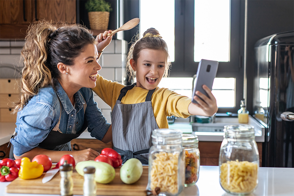 Mother and daughter cooking and laughing looking into a phone