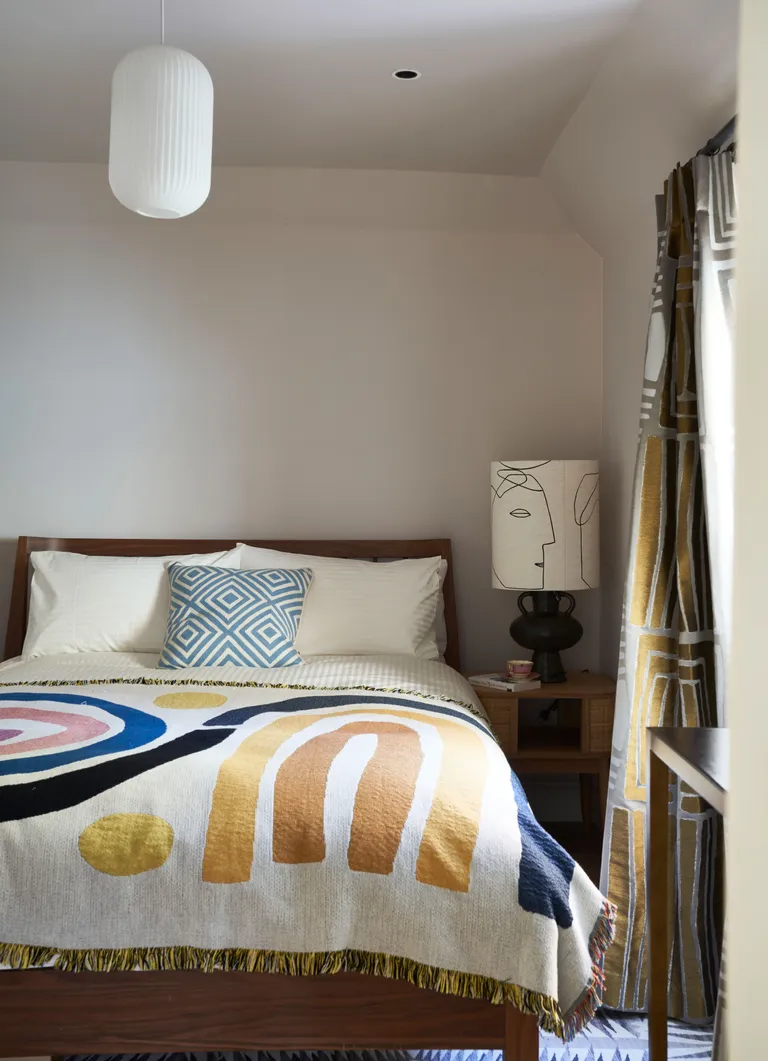 White bedroom with colorful abstract throw