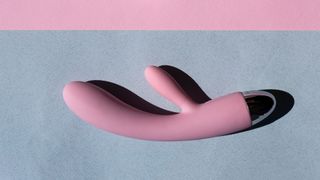 Pink silicone rabbit vibrator on grey fabric background