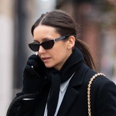 Nina Debrov wearing a black coat, white striped button down, black scarf, and snakeskin shoes