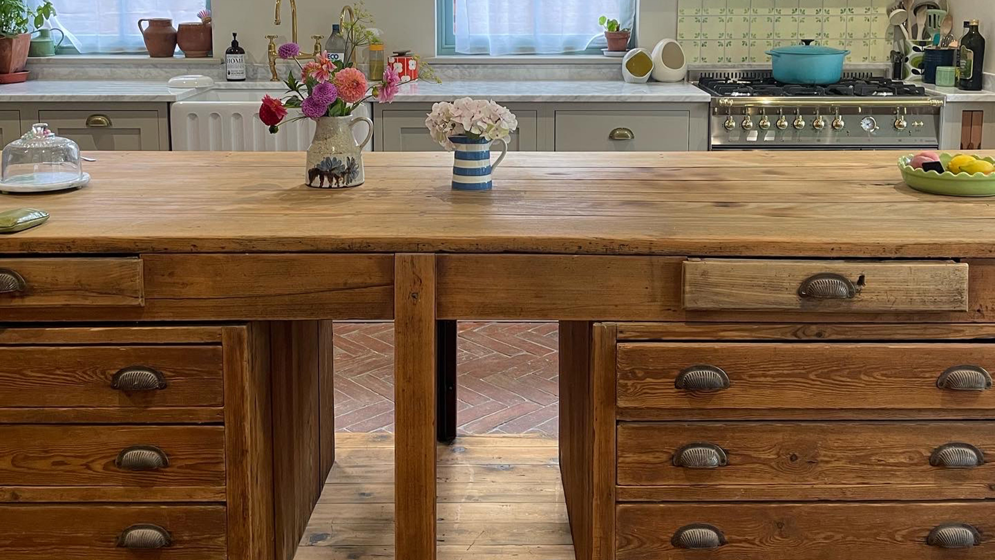 vintage wood kitchen island with brass drawer pulls and flowers on the counter