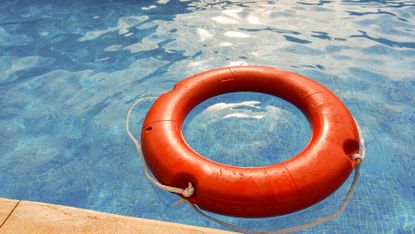An orange life ring floating in a swimming pool.