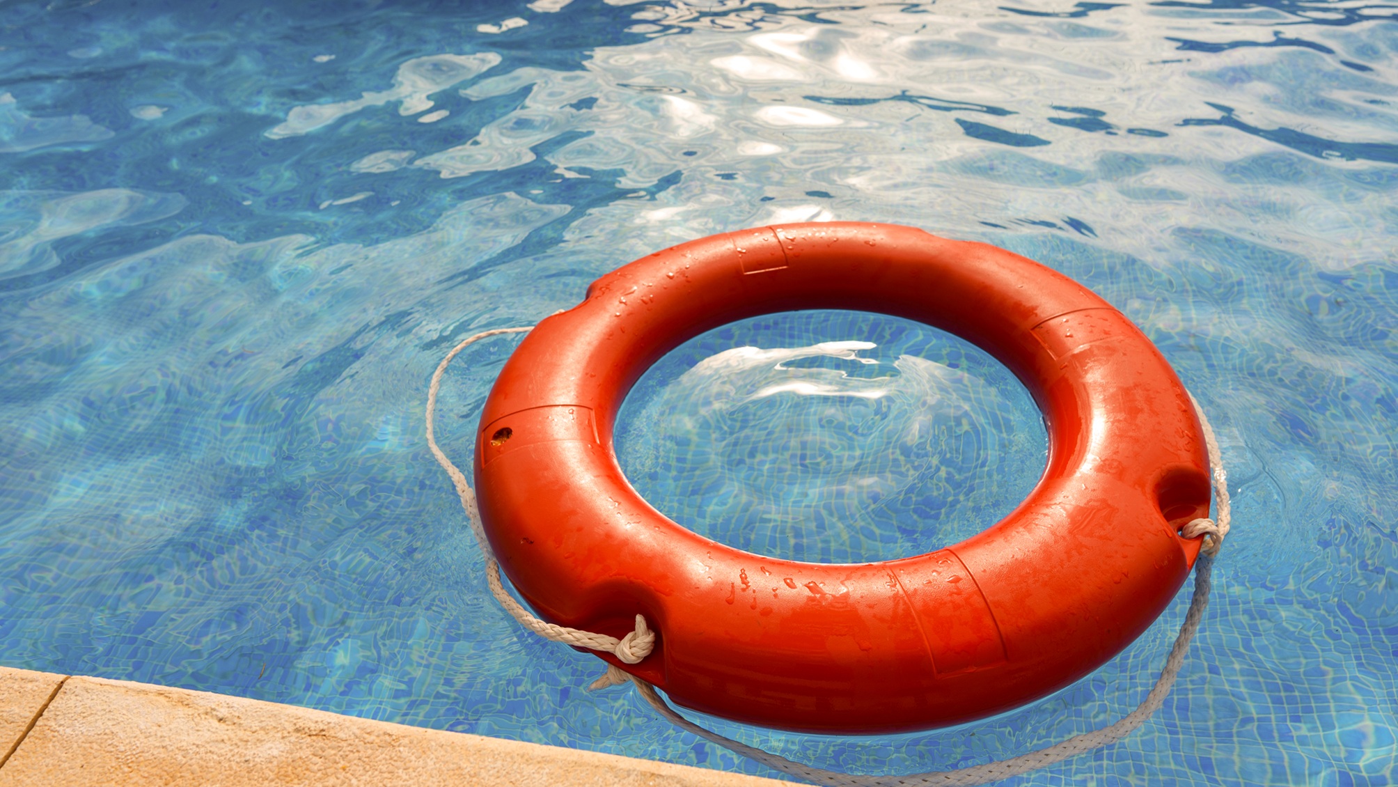 An orange life ring floating in a swimming pool.