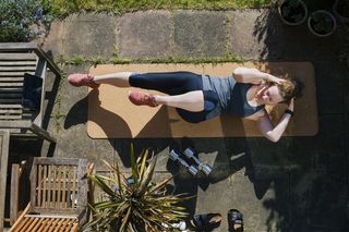 Overhead view of a woman doing core exercises on a mat in her garden