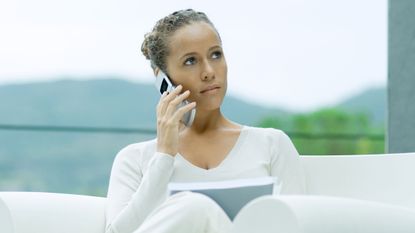 woman on couch talking on flip phone