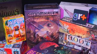 A collection of the best board games, standing in a row on a wooden table and against a dark background, with a GamesRadar+ logo visible