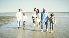 A multigenerational family walks together on the beach.