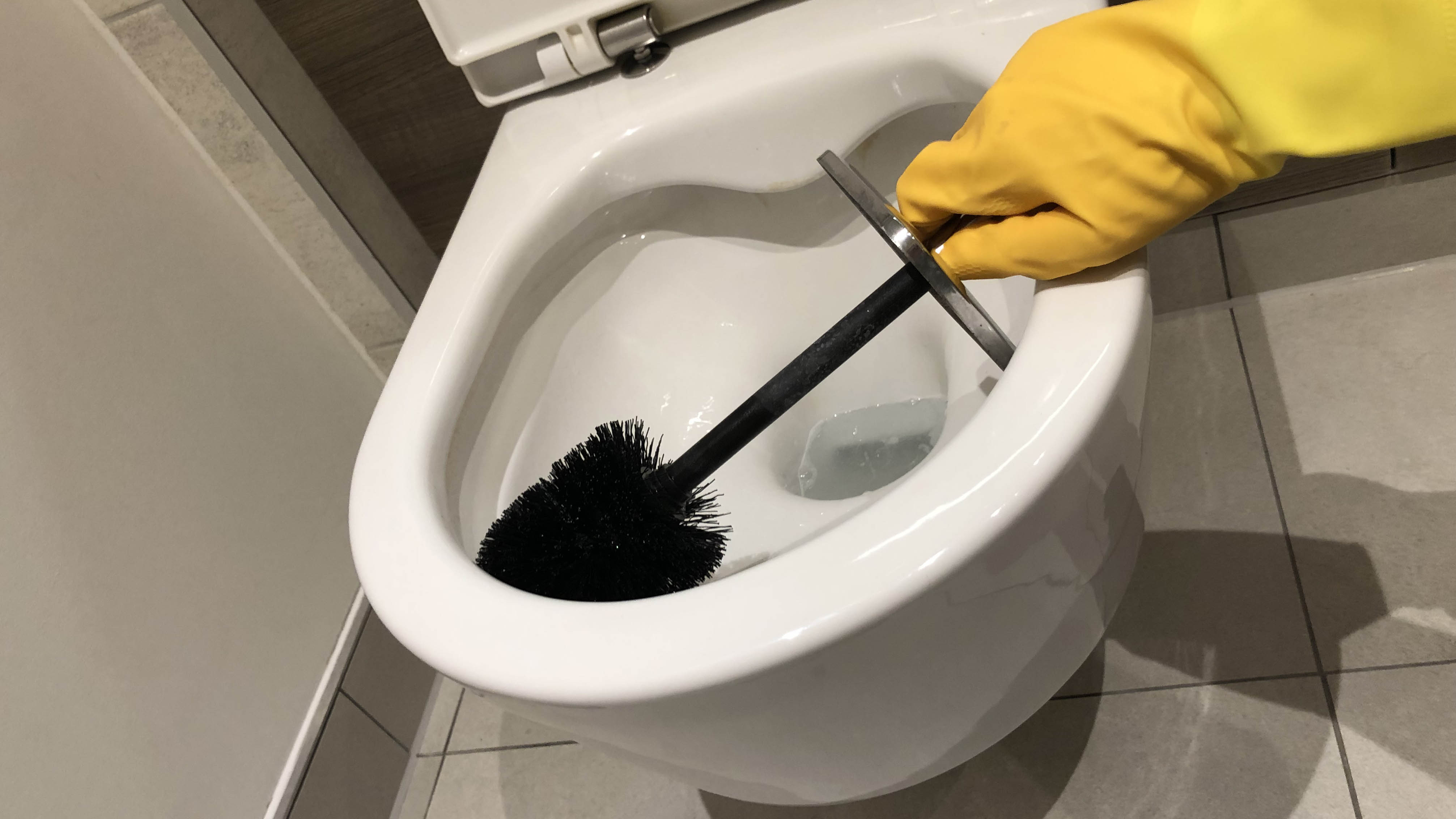 A toilet bowl is cleaned with a toilet brush