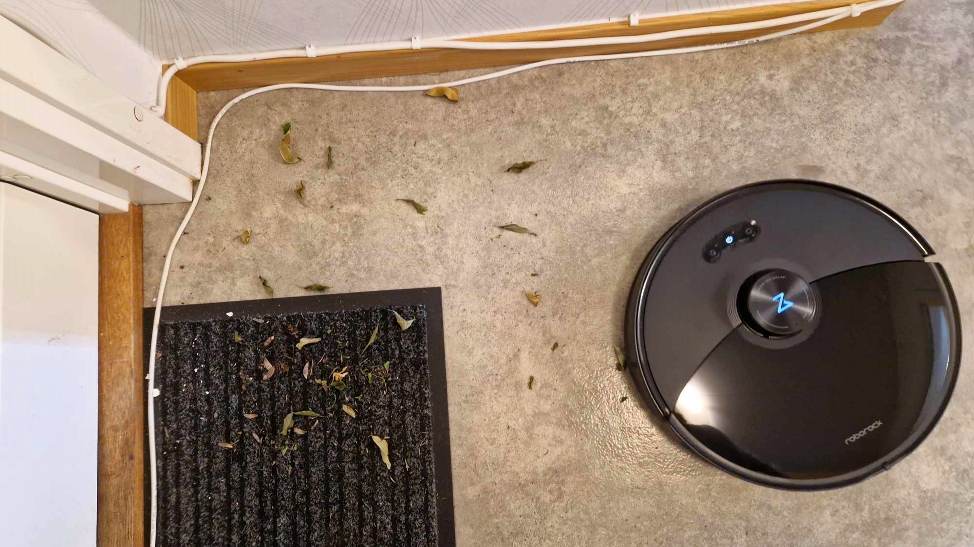 Roborock S8 MaxV Ultra siivoamassa ulkomaton vieressä olevia lehtiä