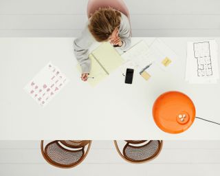 Saskia Dijkstra at her desk. An overview of a woman sitting at a table with sketch papers on it.
