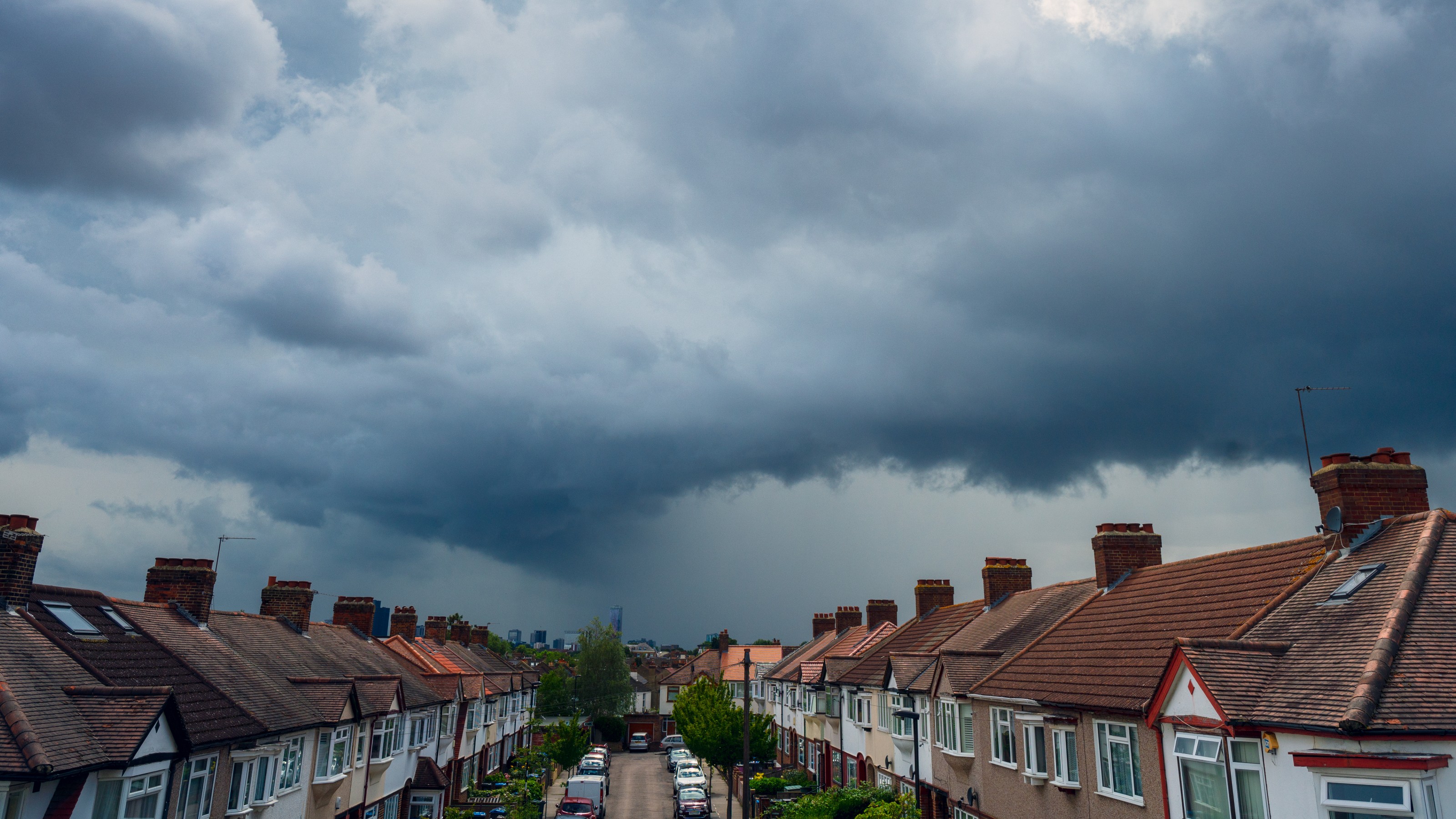 Storm clouds over a London street of houses and parked cars