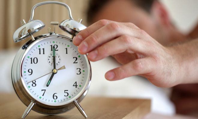 Man turning off alarm clock