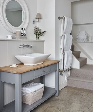 An example of how to design a bathroom showing a neutral bathroom with stairs next to a towel rail and a wooden vanity
