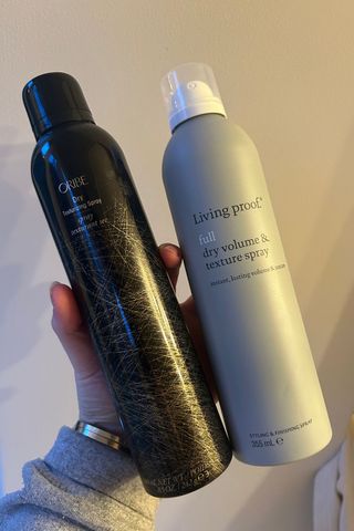 Tori holding Oribe Dry Texturising Spray and Living Proof Dry Volume and Texture Spray