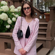 Photo of Who What Wear editor Allyson Payer wearing pink tweed skirt suit, black tank top, sunglasses, and black bag standing in front of New York street.