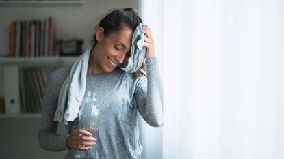 woman sweating and holding a water bottle after a workout