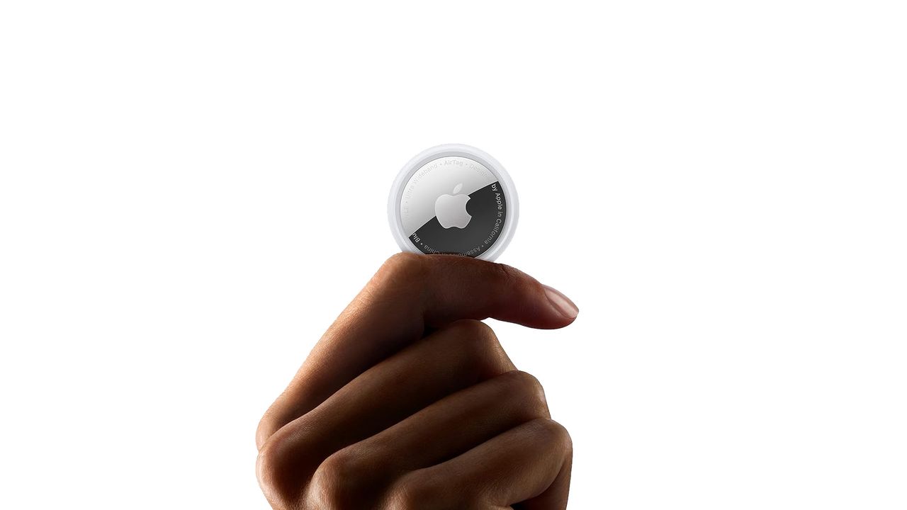 An Apple Airtag held in a hand.