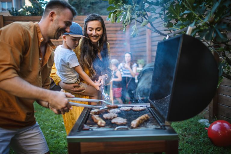 Photo of young happy family having a barbecue party in backyard
