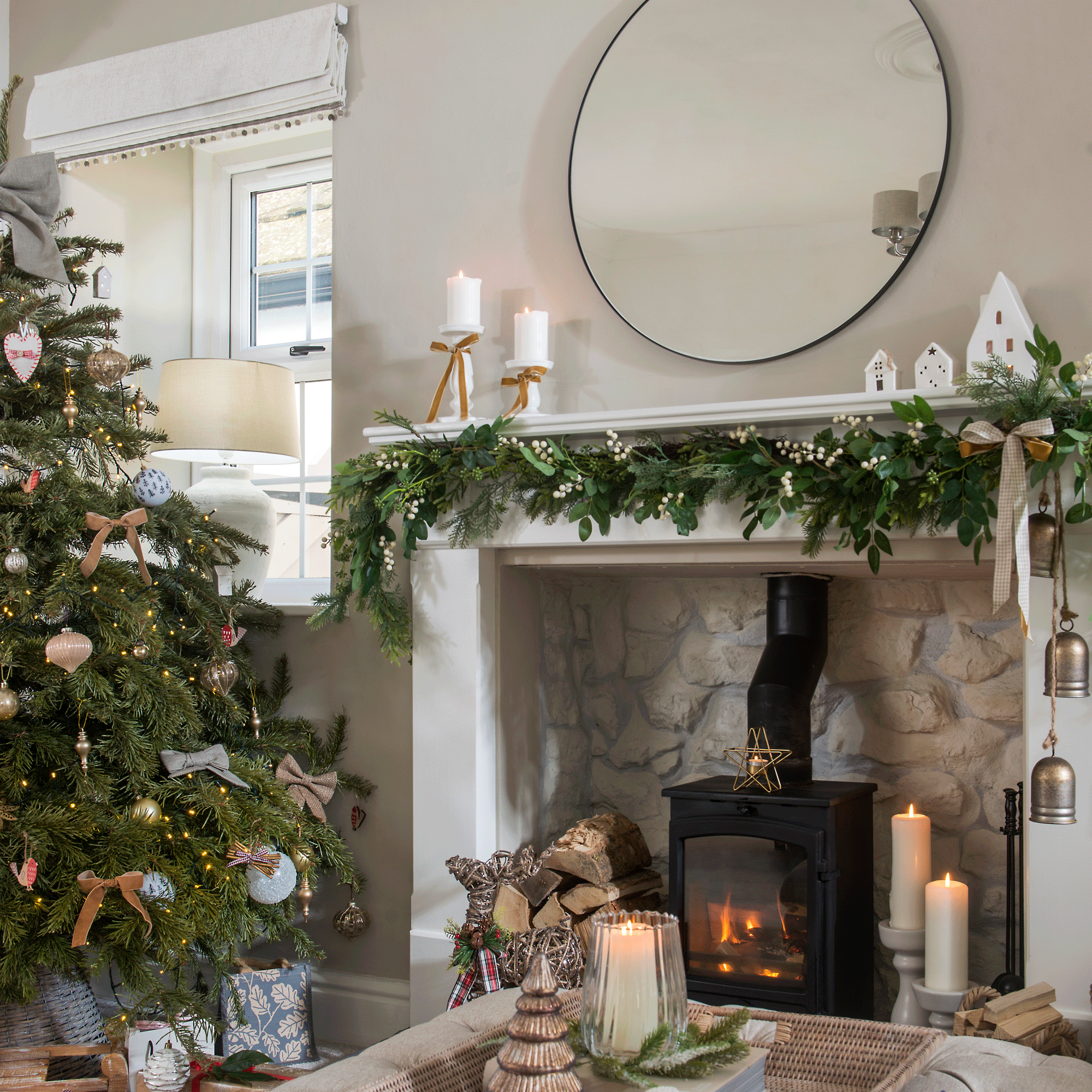 a neutral Christmas living room with a woodburner and mantelpiece, a Christmas tree, candles and festive foliage