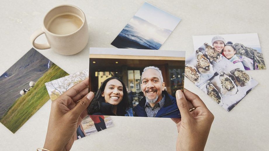 Hands holding a photo of a smiling man and women