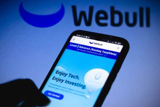 Person looking at Webull trading app on phone with Webull logo in background