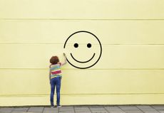 Girl drawing smiley face on to a wall, inspirational wall art