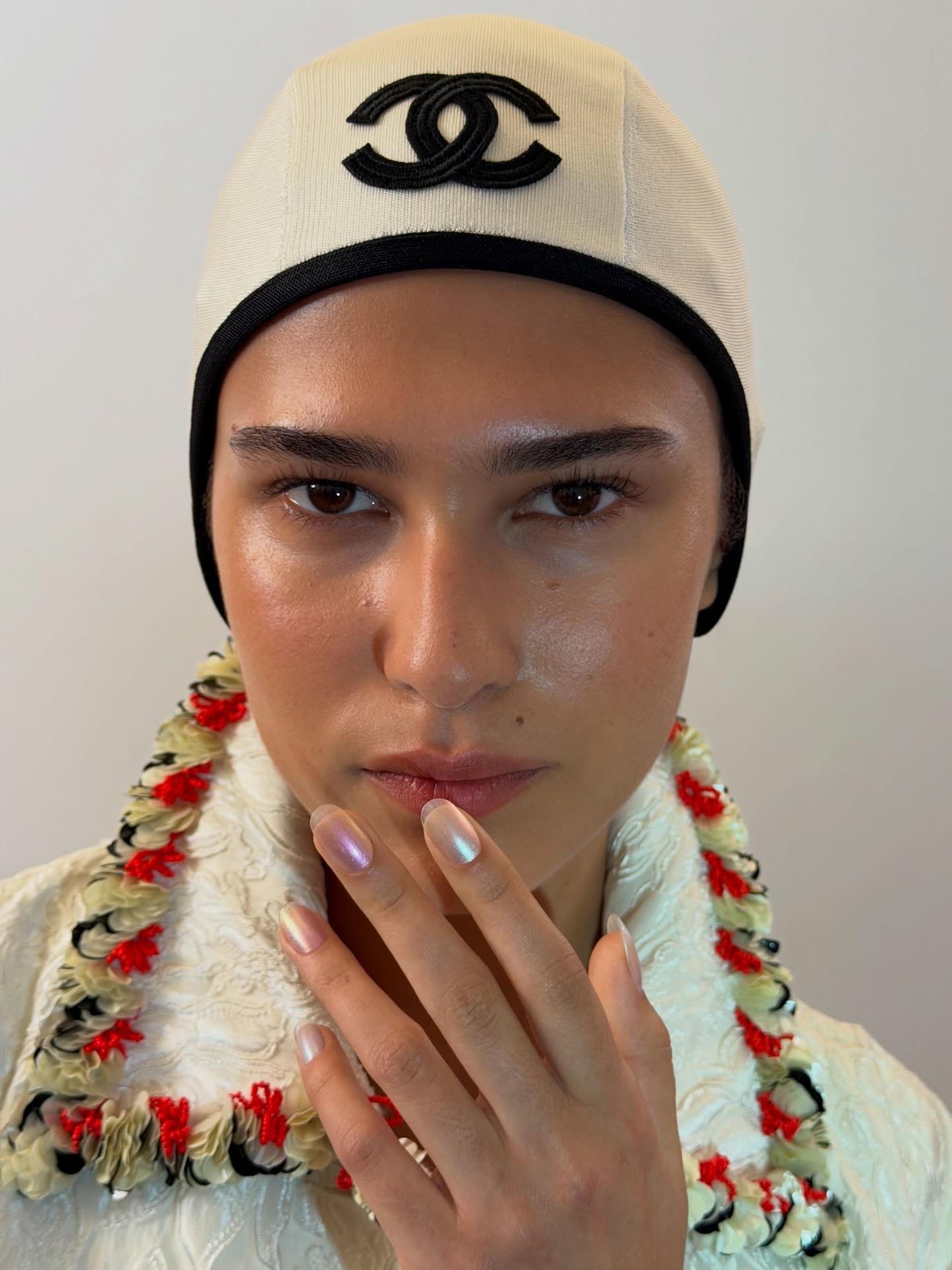 An image of a model wearing Chanel Cruise 26/27 and multicolored chrome nails.