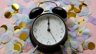 An alarm clock surrounded by confetti from a New Year's Eve party