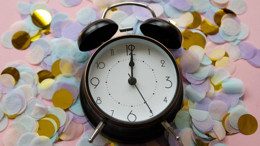 An alarm clock surrounded by confetti from a New Year&#039;s Eve party