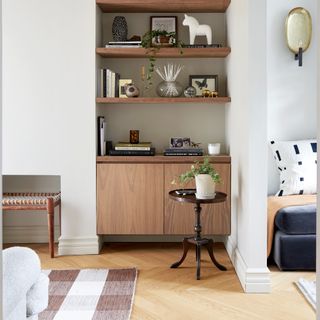 A white living room with wooden shelves and a floating cabinet built into an alcove