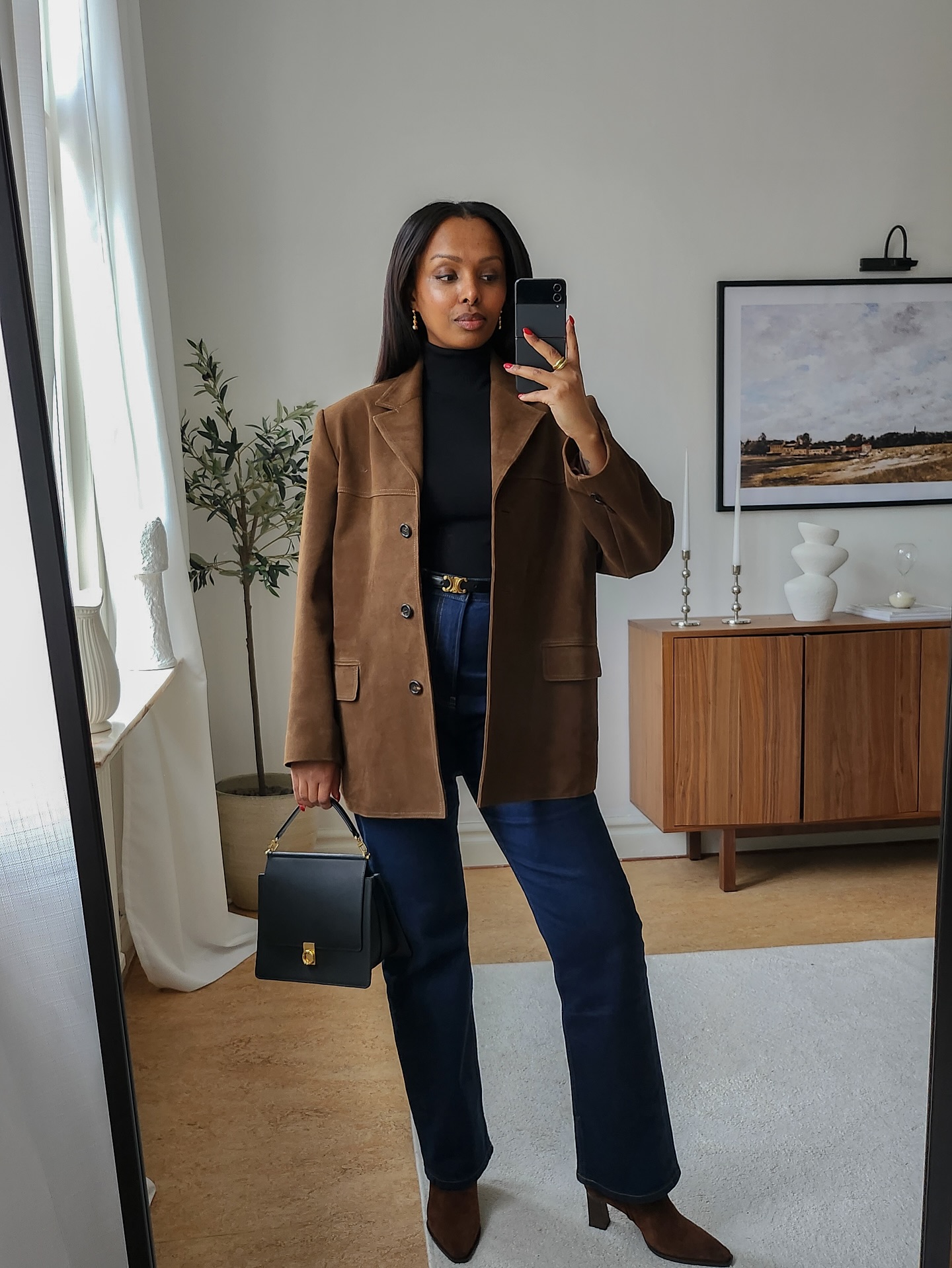 @femmeblk wears a tan suede jacket with deep blue jeans