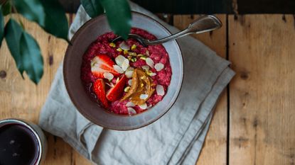 Nature's cereal -oatmeal porridge with strawberries and fruit yogurt and pistachios, peanut butter and almond in bowl. Morning concept with copy space 