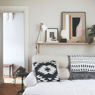 A small living room painted in an off-white colour with a boucle cream sofa at front