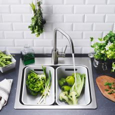 veggies with wash basin and faucet with white brick designed tiles on wall