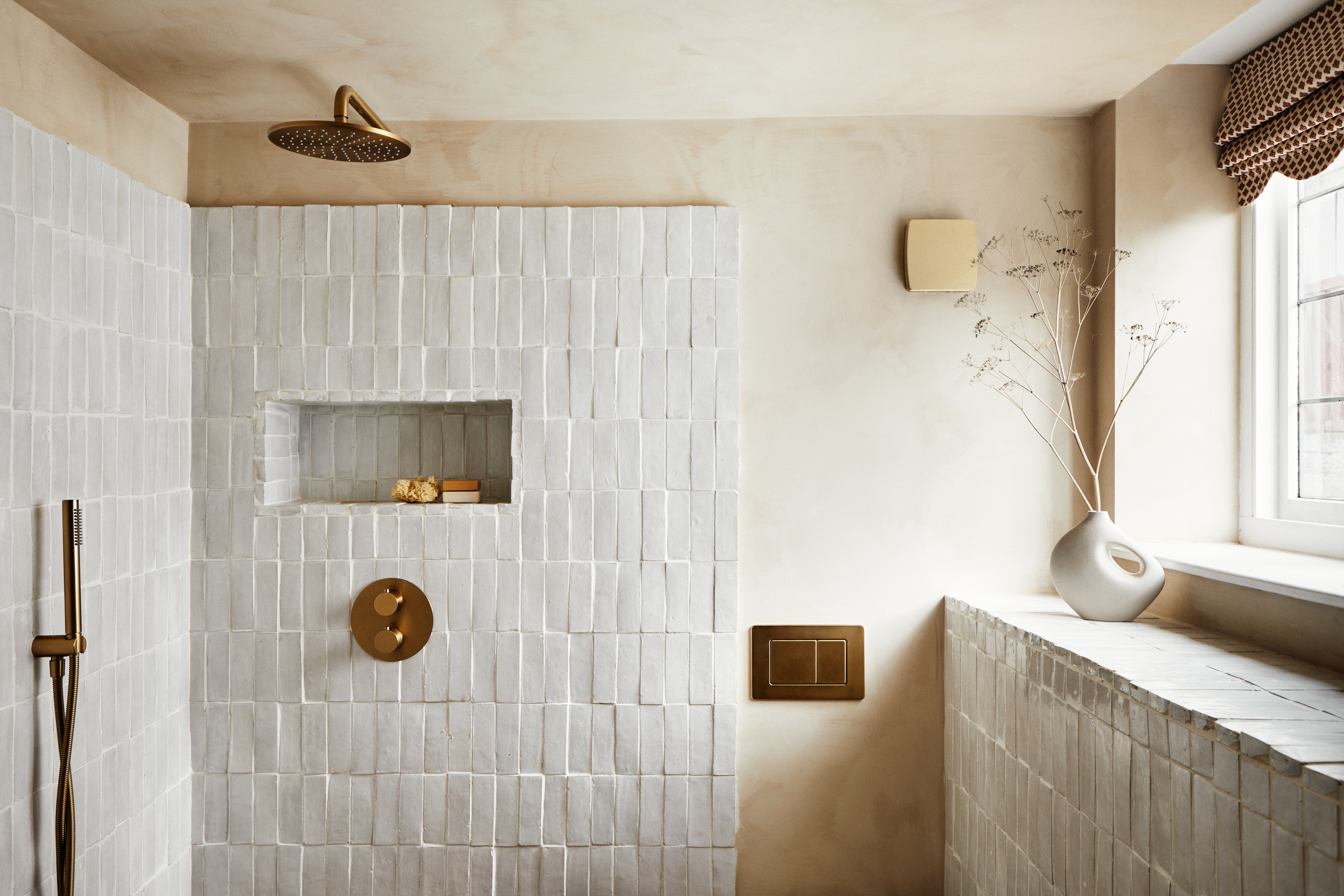 A white bathroom with long rectangular tiles and a shower space 