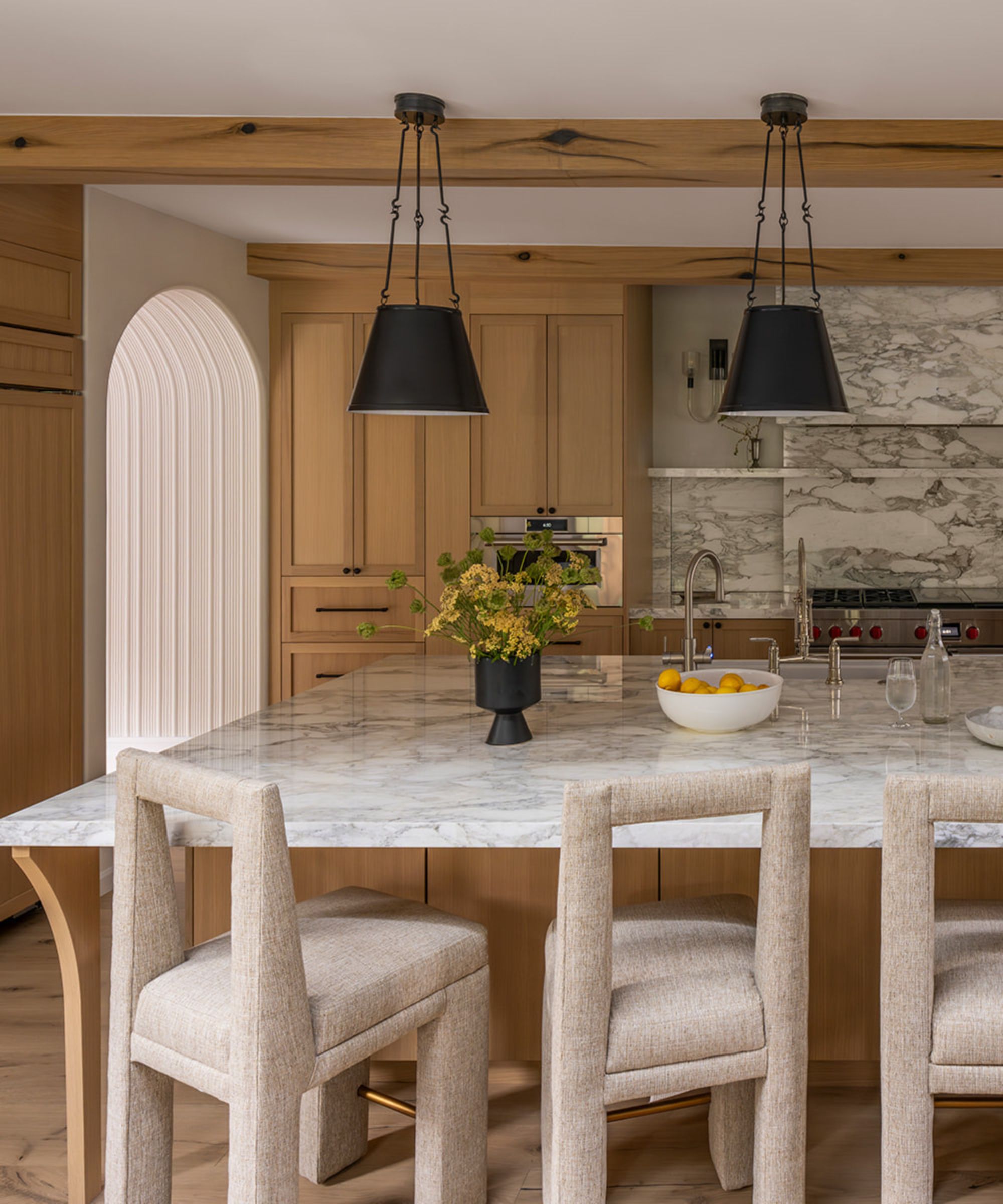 A wooden kitchen with marble countertops, and black lighting