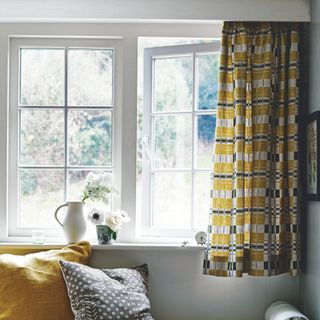 Open white framed casement window with ochre, white and black curtain and vase and jug on the window sill