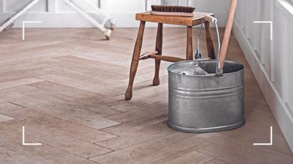 wooden parquet floor with traditional metal bucket with mop to support an article on how often should you mop your floors