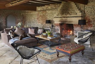 living room with sofas and rugs and fireplace in flint-and-brick house