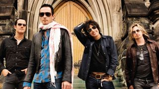 Stone Temple Pilots posing for a photograph in front of a wooden door in 2010