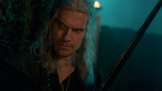 Geralt brandishes his sword in a dark setting in The Witcher season 3