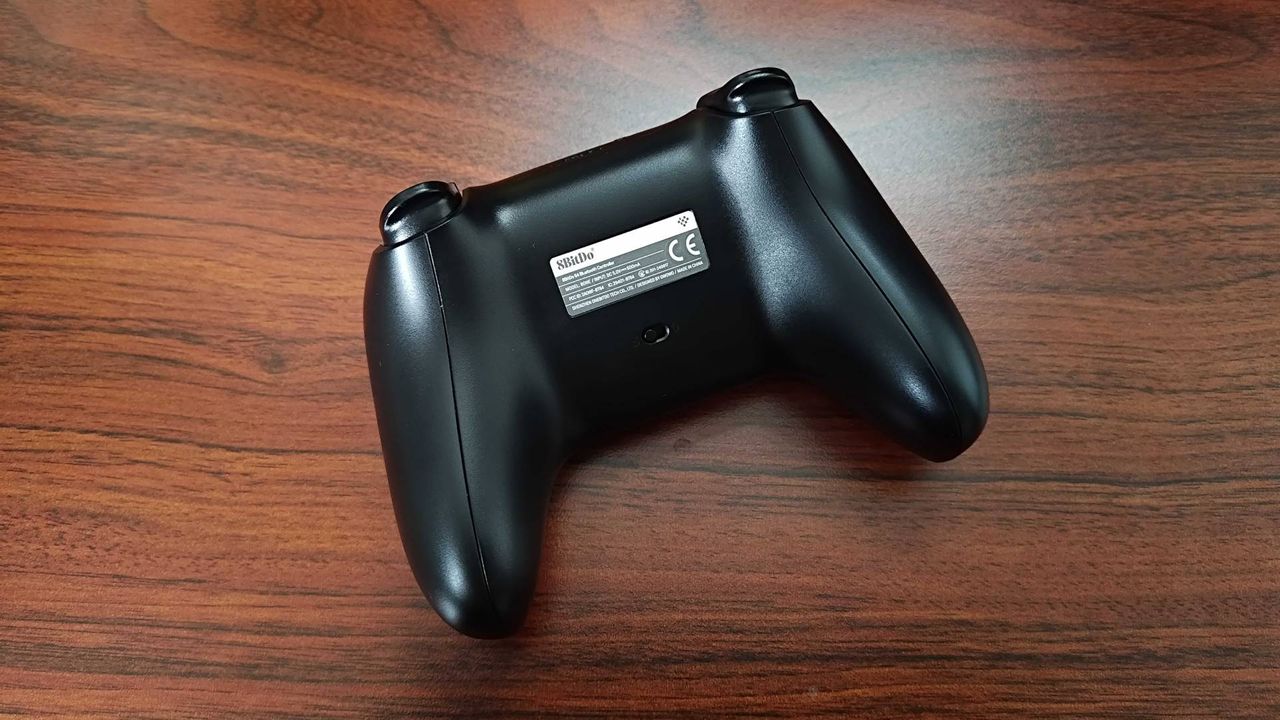 Back of 8Bitdo N64 Bluetooth controller sitting on woodgrain surface.